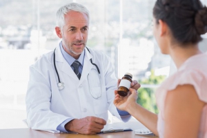 patient holding a bottle of medicine talking to a pharmacist